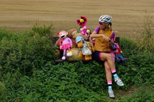Oderske vrchy. Dziewczyna w stroju kolarskim siedząca na ławce obok pluszowych zwierzątek
