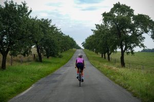 Oderske vrchy. Dziewczyna jadąca drogą wśród drzew owocowych
