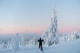 Narciarz idący przez zaspy śniegu przy zachodzącym słońcu