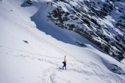 Narciarz freeride podchodzący z nartami na plecach na stromym zboczu