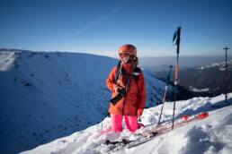 narciarka w kasku w głębokim śniegu, trzyma aparat fotograficzny
